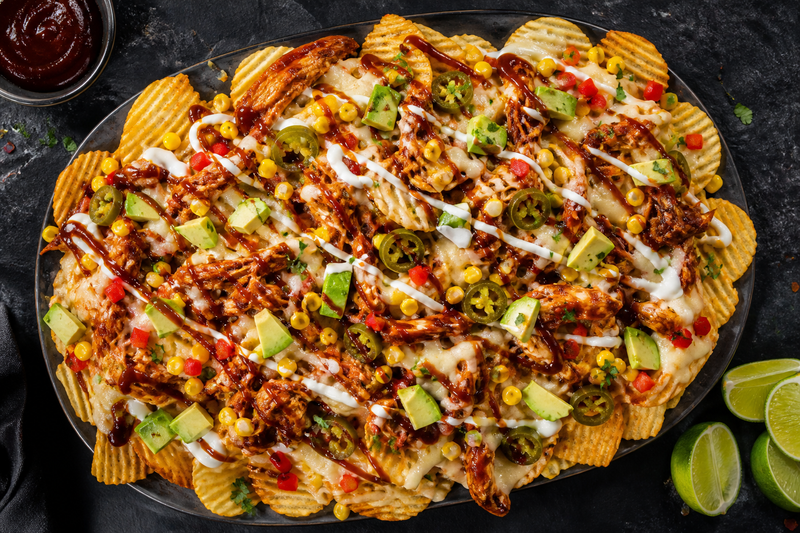 A platter of RUFFLES potato chip nachos loaded with BBQ chicken, melted cheese, corn, jalapeno and avocado