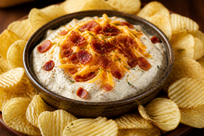 A creamy bacon ranch cheddar dip in a bowl surrounded by a ring of RUFFLES potato chips